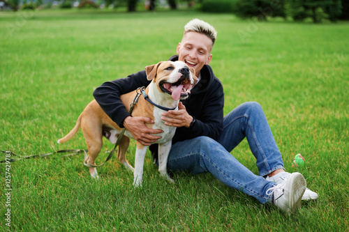 Generated imageGuy and his dog, american bulldog, nature. The dog and the owner are smiling. A dog with a collar and leash opens its mouth and sticks out its tongue.
