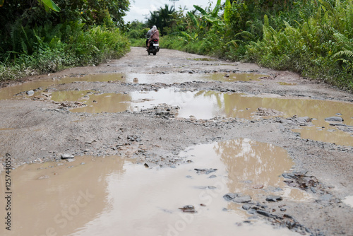 Damaged potholed roads that are flooded after rain. hampering village transportation access to the city. Kubu Raya, West Kalimantan - December 14, 2024