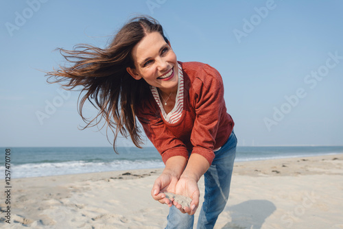 Woman with long hair holding sand at beach photo