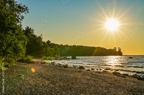 Beautiful sunset on the beach of Narva, Estonia over the Gulf of Finland or Baltic Sea in summer with the sun on the horizon over the sea photo