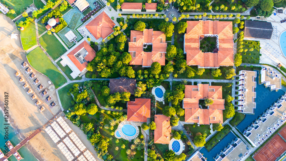 Fototapeta premium Aerial view of a luxury beachfront resort with private villas, pools, and lush gardens