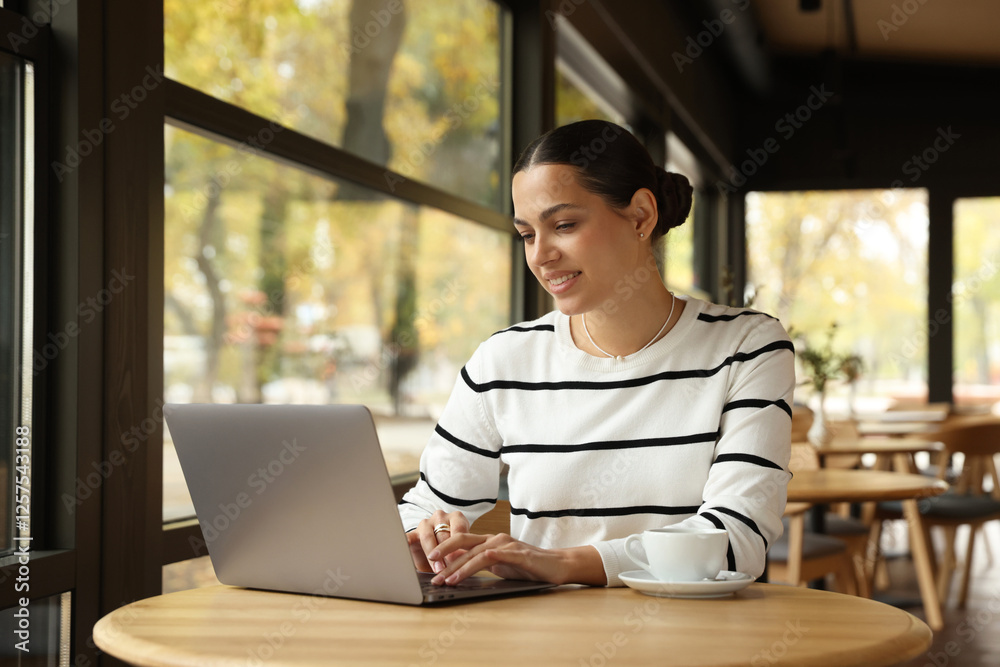 Woman working on laptop at table in cafe Woman working on laptop at table in cafe