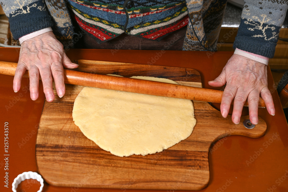Elderly person rolling dough on wooden board in a cozy kitchen during a baking session