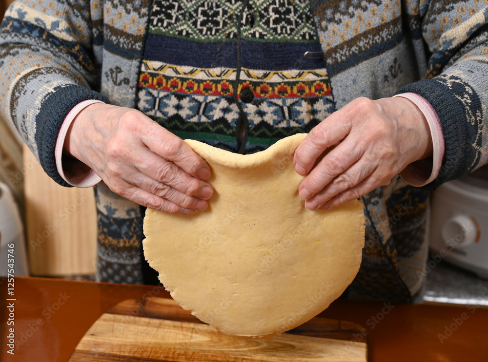 Elderly person preparing dough with traditional techniques in a cozy kitchen