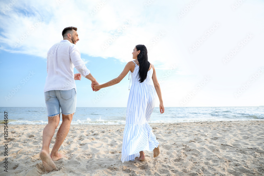 Happy young couple walking together on beach, back view Happy young couple walking together on beach, back view