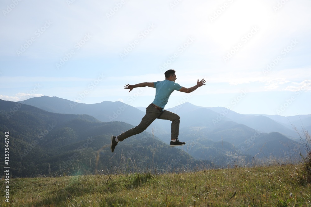 Sporty man running on grassy hill in mountains Sporty man running on grassy hill in mountains