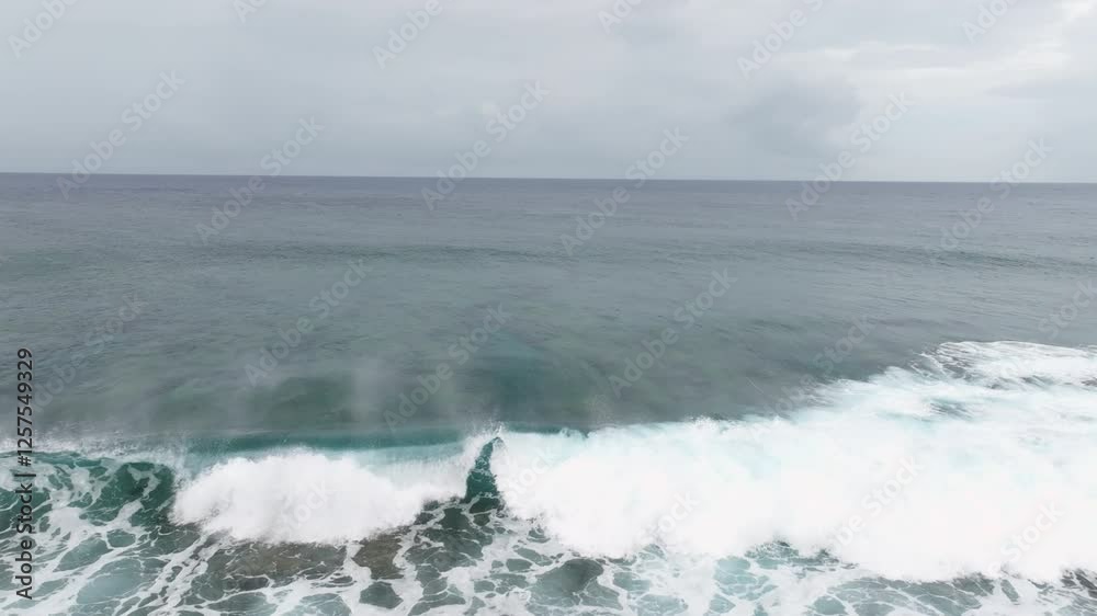 Aerial tracking right slow motion as waves break on shallow fringing reef in ocean water