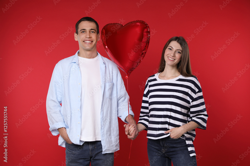 Lovely couple with heart shaped balloon on red background. Valentine's day celebration Lovely couple with heart shaped balloon on red background. Valentine's day celebration