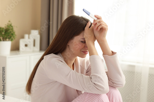 Upset woman with negative pregnancy test at home