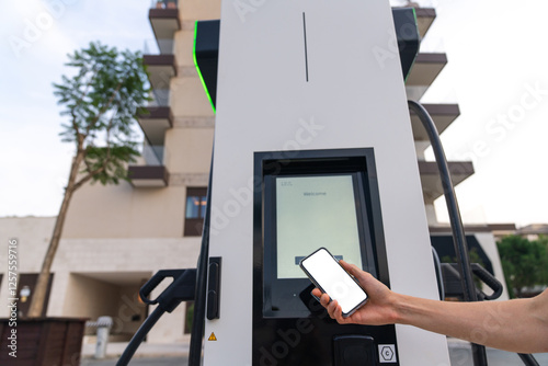 Man uses NFC on his smartphone for paying by chaging electric car photo