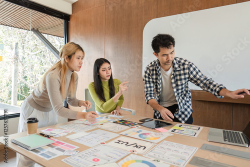 Diverse team of designers collaborating on UX UI project in modern office. photo