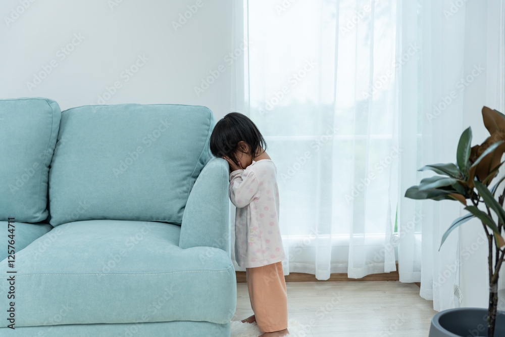 little asian children kid playing hide and seek standing behind the sofa, Adorable child having fun in the home. happy family have fun with kids, activity, learning, activity, game, meditation little asian children kid playing hide and seek standing behind the sofa, Adorable child having fun in the home. happy family have fun with kids, activity, learning, activity, game, meditation
