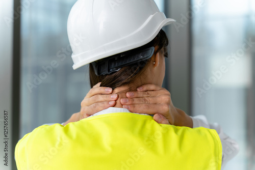 Female engineer in yellow vest suffering from pain in her neck