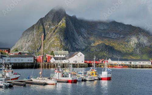 fishing boats in a harbor in fjord of Norway and mountain under clouds