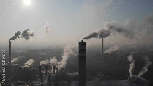 Industrial chimneys releasing smoke into atmosphere at sunrise