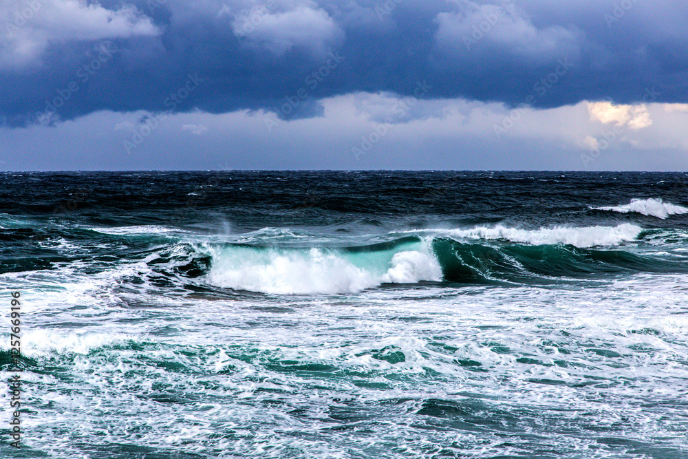 storm clouds over waves breaking on the shore storm clouds over waves breaking on the shore