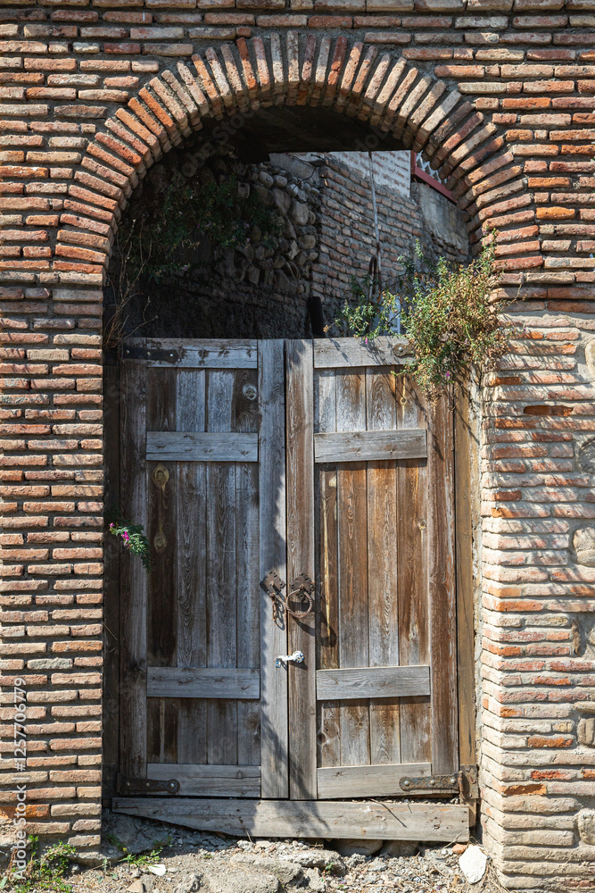 An old wooden gate in a stone arch An old wooden gate in a stone arch