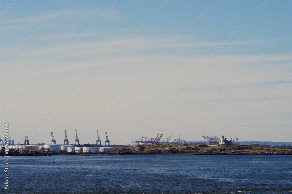 Bayonne Energy Center with cranes and tanks by a calm sea under a clear sky in New Jersey Bayonne Energy Center with cranes and tanks by a calm sea under a clear sky in New Jersey