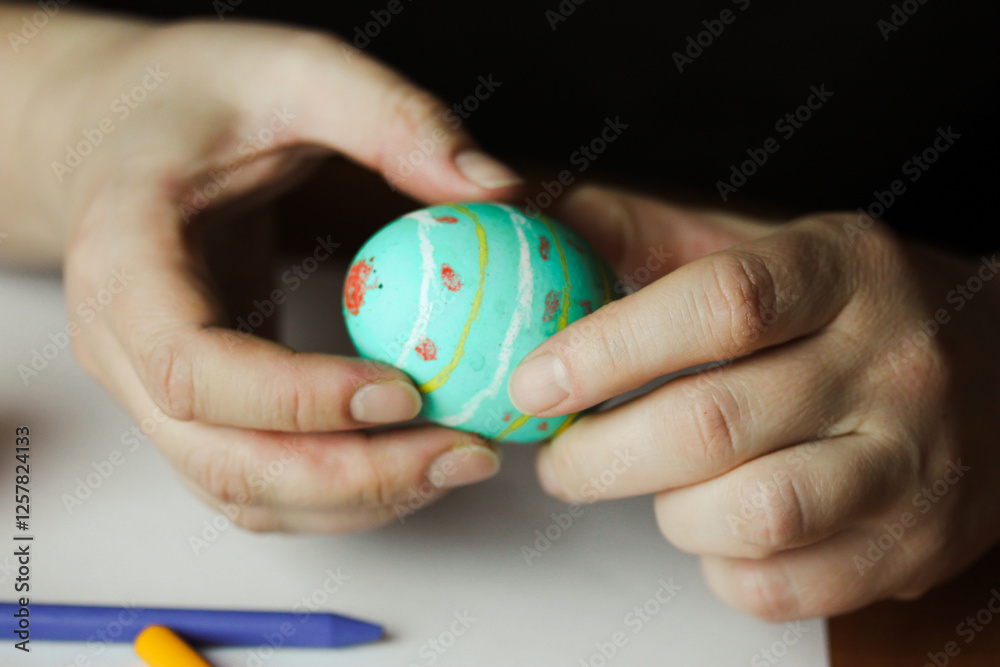 Painting Easter eggs with colourful wax crayons. Easter egg in women's hands. People preparing for Easter in April. Traditional annual spring holiday. Painting Easter eggs with colourful wax crayons. Easter egg in women's hands. People preparing for Easter in April. Traditional annual spring holiday.