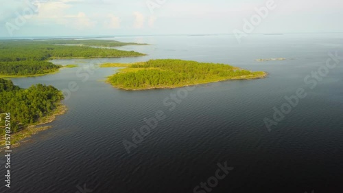 Atemberaubender Drohnenflug über einen malerischen Leuchtturm am Vänernsee in Schweden bei Sonnenuntergang – Spiegelndes Wasser und idyllische Landschaft in goldenem Licht photo