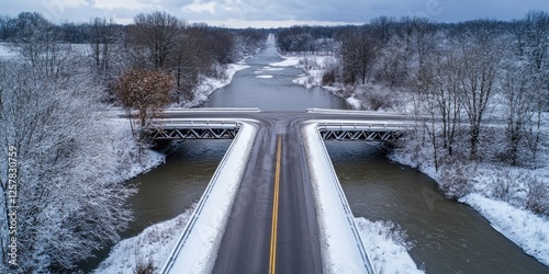 A snowy winter day where a salt truck works to clear ice and keep the road passable for traffic across a river. photo