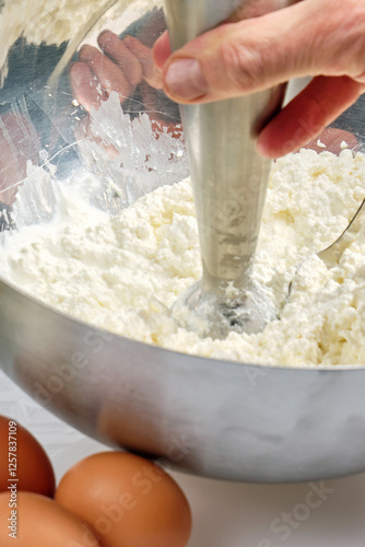 The cook mixes cottage cheese with a mixer to obtain a homogeneous mass