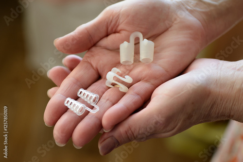Hands holding anti-snoring device for nose. Selective focus.