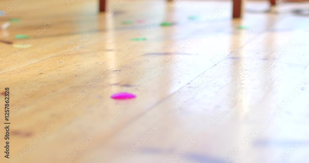 A vibrant array of colorful confetti is artfully scattered across a wooden floor background A vibrant array of colorful confetti is artfully scattered across a wooden floor background