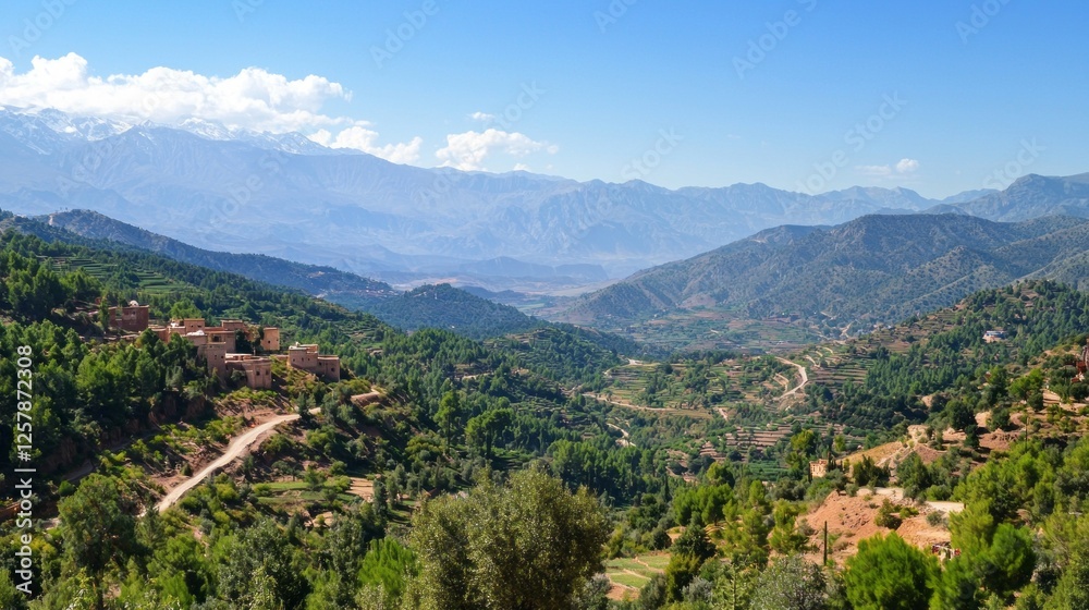 Obraz premium Winding pathways carve through the stunning Atlas Mountains, showcasing terraced fields and charming villages under a clear blue sky. Nature thrives, inviting exploration and peace