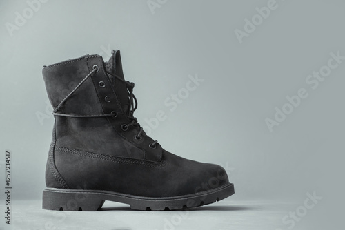 New stylish black suede leather tracking boots grey background.  Winter footwear concept. Copy space for a free text photo