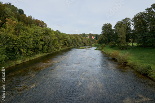 Wallpaper Mural Serene River Landscape with Cozy Cottages Nestled in Lush European Greenery Under Dramatic Twilight Sky. Tranquil European Riverside Village at Dusk: Picturesque Houses Nestled Among Lush Greenery Torontodigital.ca