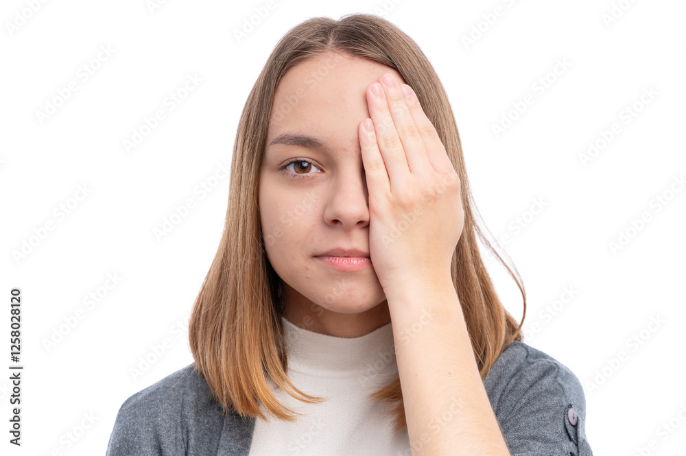 A young woman with straight hair covering one eye with her hand against a white background. A young woman with straight hair covering one eye with her hand against a white background.