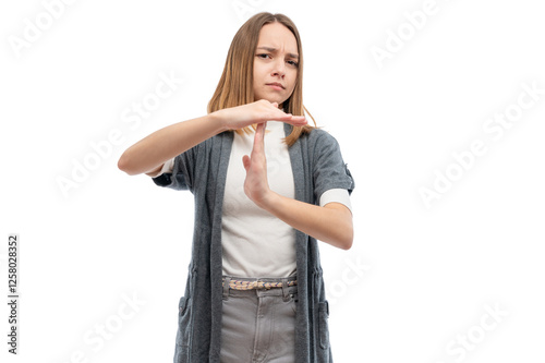 A young woman with a serious expression making a stop gesture with her hands against a white background.