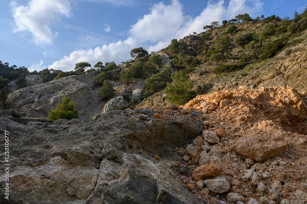 Rocky terrain under a bright blue sky with scattered clouds and lush greenery in a serene landscape Rocky terrain under a bright blue sky with scattered clouds and lush greenery in a serene landscape