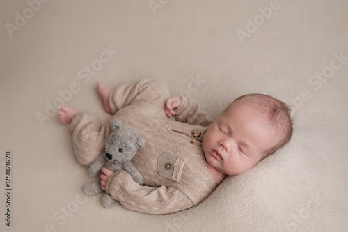 Peaceful Newborn Sleeping with Teddy Bear in Cozy Outfit photo