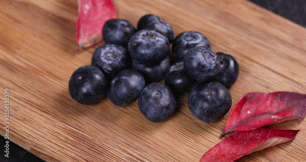 Fresh blueberries and red autumn leaves on wooden board