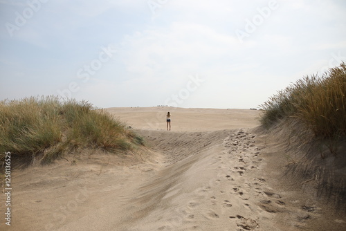 Fototapeta Naklejka Na Ścianę i Meble -  Woman walking in between the sand dunes