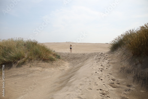 Fototapeta Naklejka Na Ścianę i Meble -  Woman walking in between the sand dunes