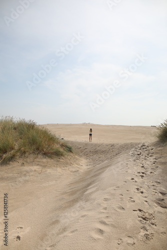 Fototapeta Naklejka Na Ścianę i Meble -  Woman walking in between the sand dunes