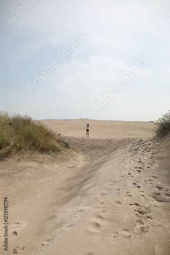 Fototapeta Naklejka Na Ścianę i Meble -  Woman walking in between the sand dunes