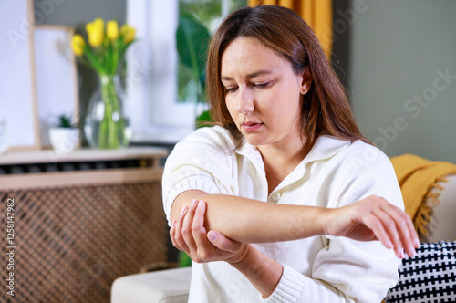 Young woman suffering from pain in elbow at home
