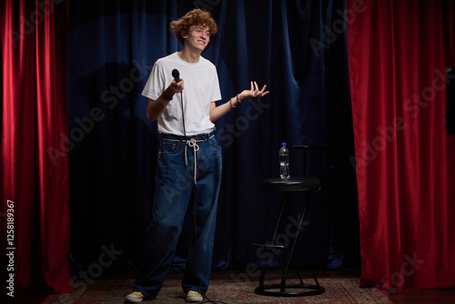 Red-haired comedian engaging audience on stage with microphone in hand, standing confidently while delivering a performance