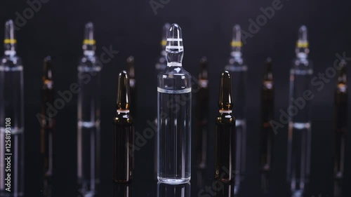 Ampoules with medicine on glossy black background. Pharmaceutical products, vaccination and beauty concept. Dolly shot 4k