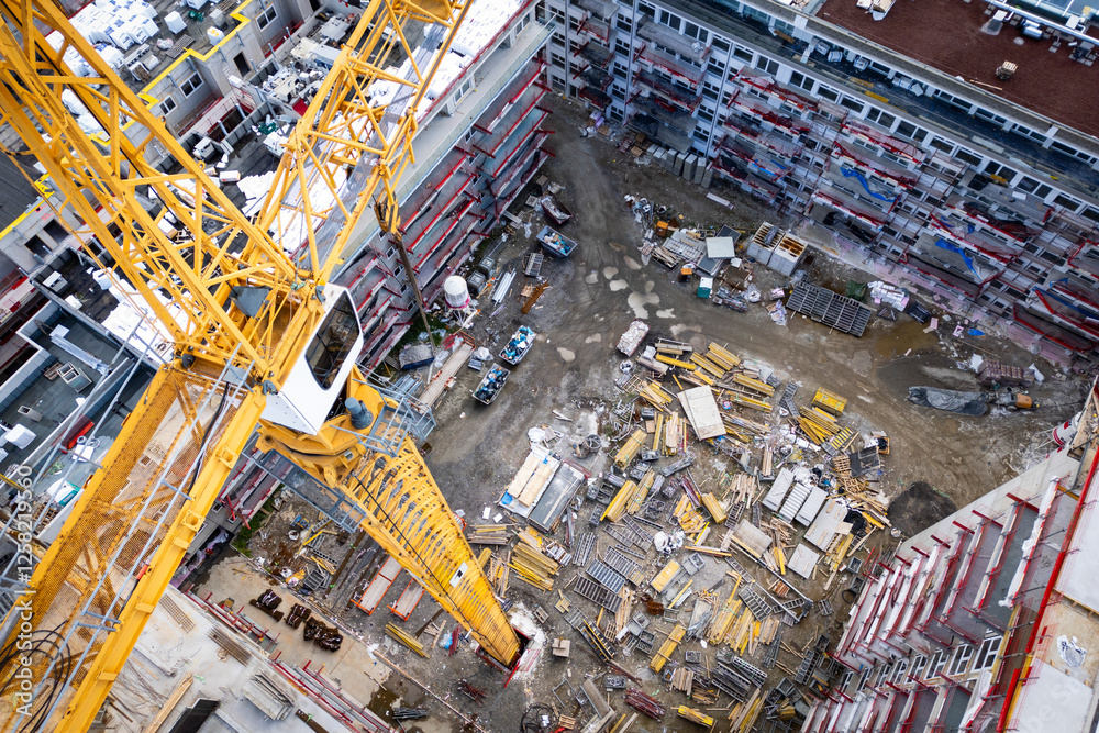 Naklejka premium Building under construction with a tower crane and building materials. Huge construction site for apartment buildings.