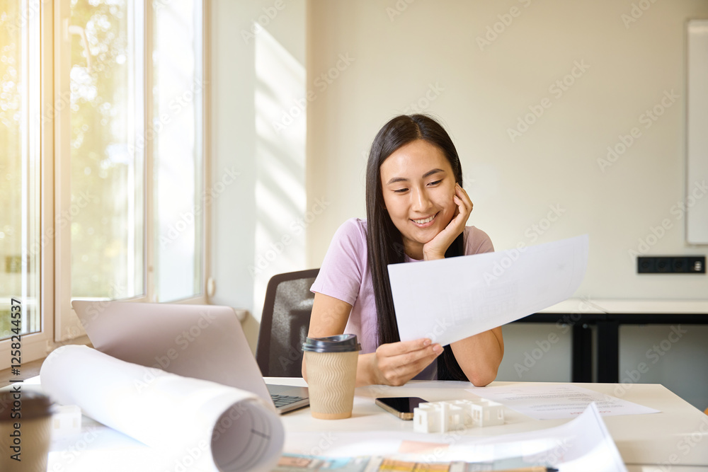 Female studies the design documentation with a smile Female studies the design documentation with a smile