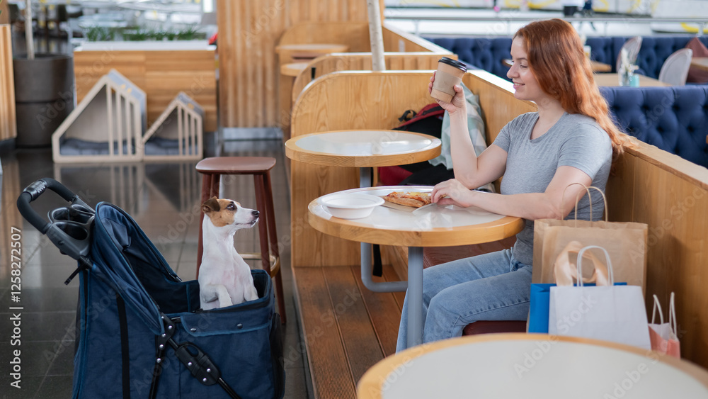 Caucasian woman having lunch in a cafe with her Jack Russell terrier dog in a stroller. Caucasian woman having lunch in a cafe with her Jack Russell terrier dog in a stroller.