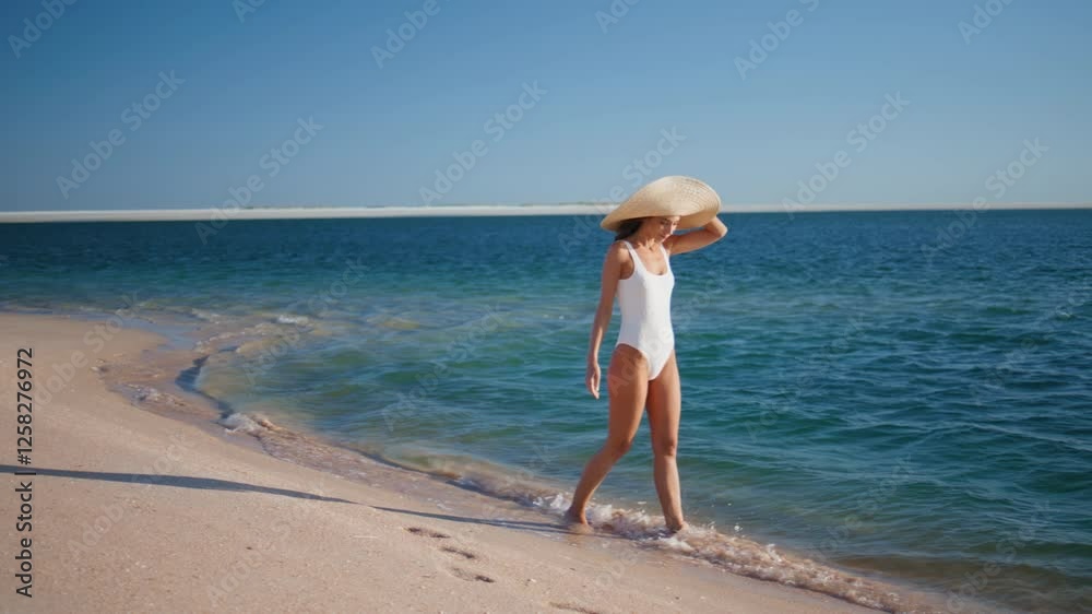 Relaxed lady stepping waves wearing straw hat. Carefree woman walking beach Relaxed lady stepping waves wearing straw hat. Carefree woman walking beach