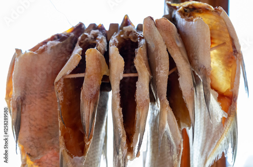 Dried fish hanging on a rack in a coastal market during daylight hours photo