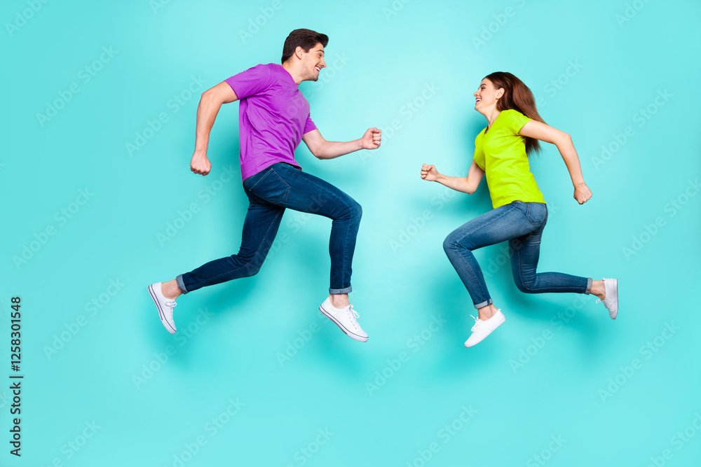 Full length body size profile side view of nice attractive sportive active cheerful cheery couple running jumping in air having fun isolated over bright vivid shine vibrant green turquoise background Full length body size profile side view of nice attractive sportive active cheerful cheery couple running jumping in air having fun isolated over bright vivid shine vibrant green turquoise background