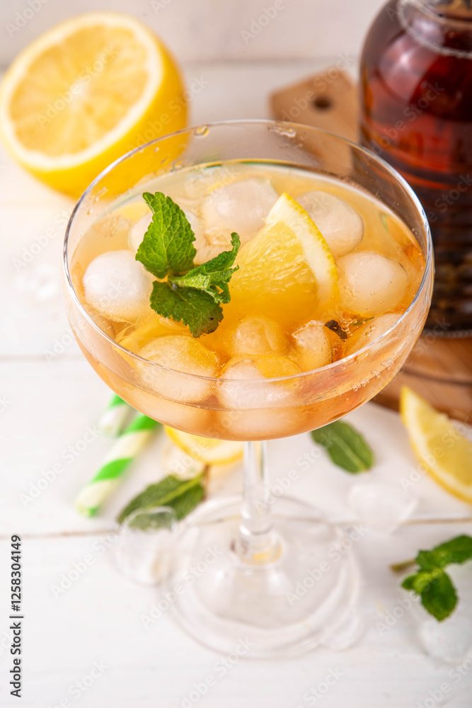 Infused tasty iced tea cocktails martini cocktail with lemon and mint, tasty refreshing non-alcohol mocktail on white wooden table background Infused tasty iced tea cocktails martini cocktail with lemon and mint, tasty refreshing non-alcohol mocktail on white wooden table background